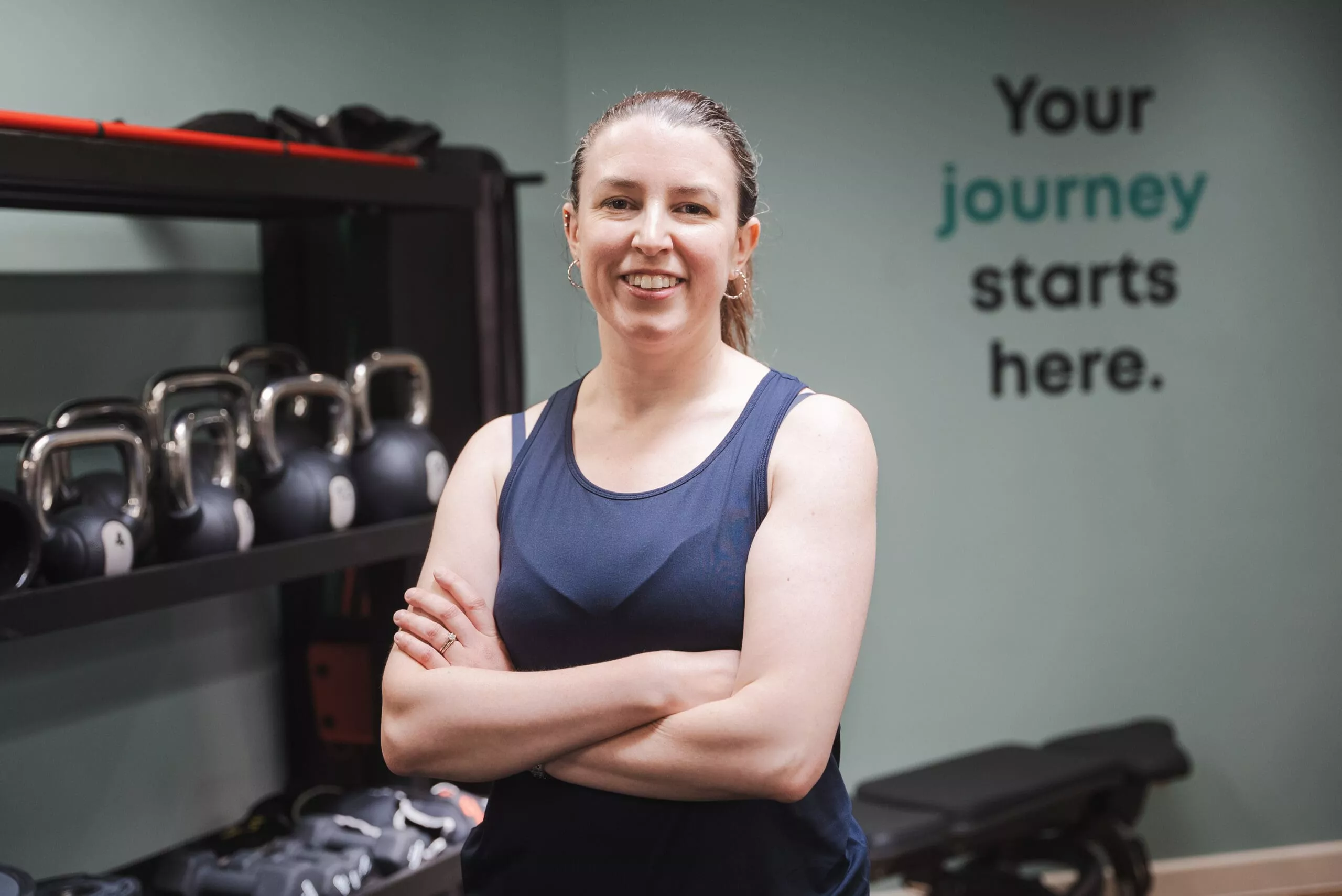 woman standing in a gym with her arms crossed