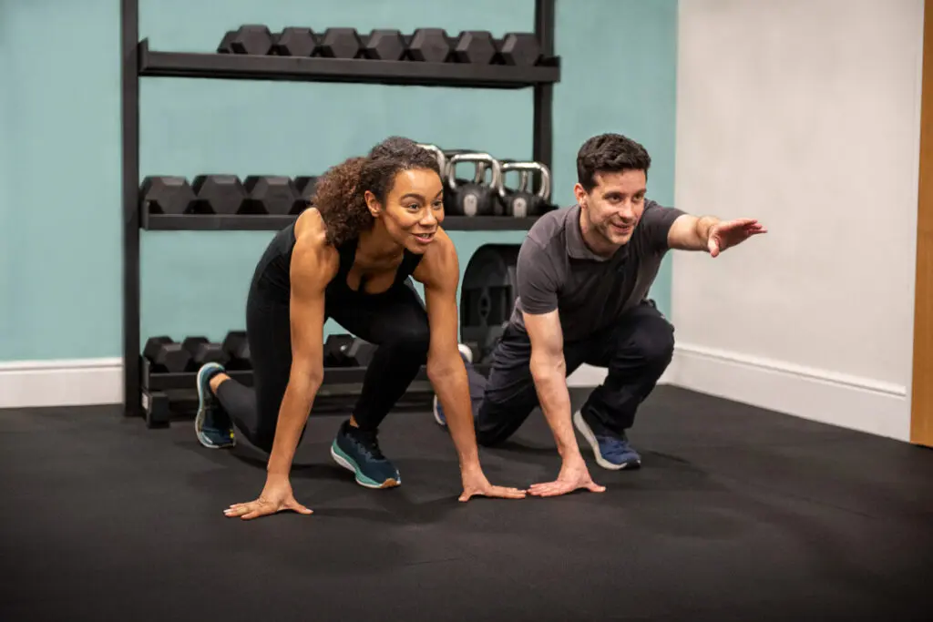 man and a woman doing push ups in a gym